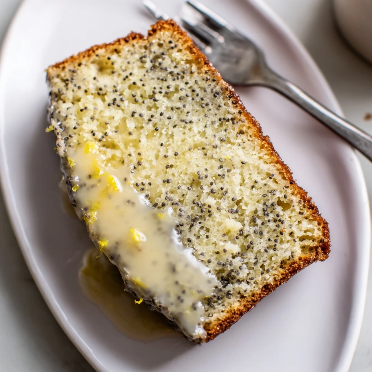 A lovely slice of Glazed Lemon Poppy Seed Cake, offering a delightful tangy and sweet experience.