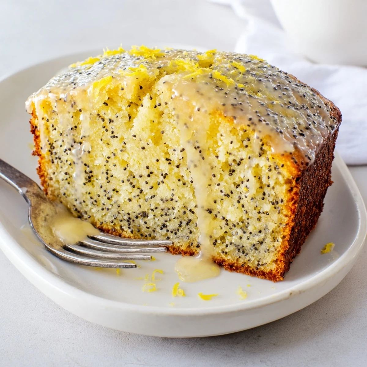 Moist Glazed Lemon Poppy Seed Cake, with a drizzle of tangy lemon glaze and lemon zest.