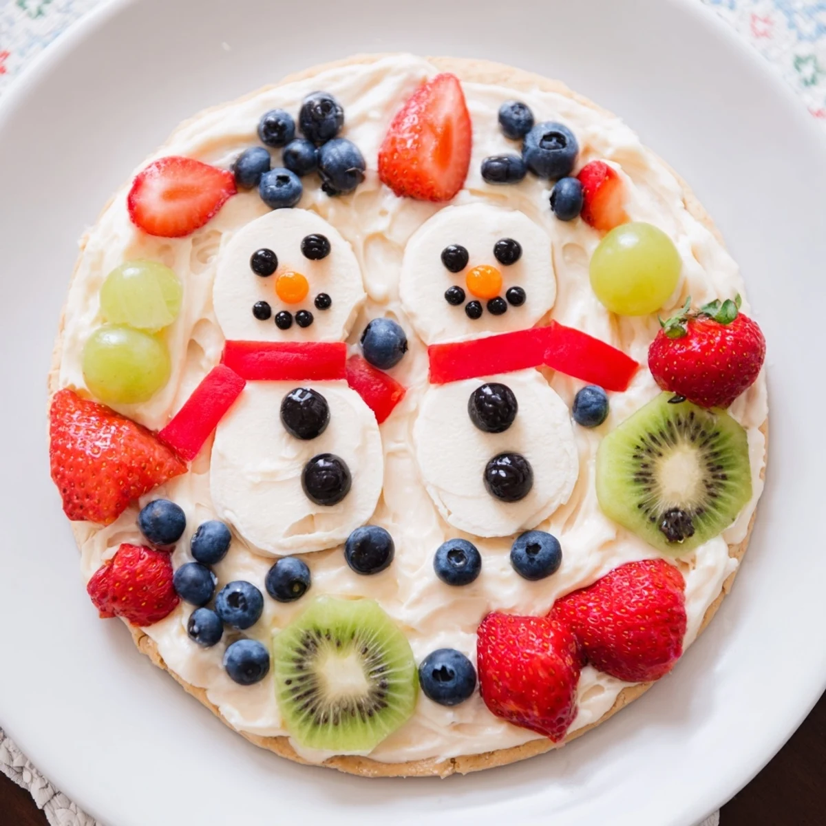Melting Snowman Fruit Pizza: a delightful dessert pizza adorned with colorful fruit, ready to eat.