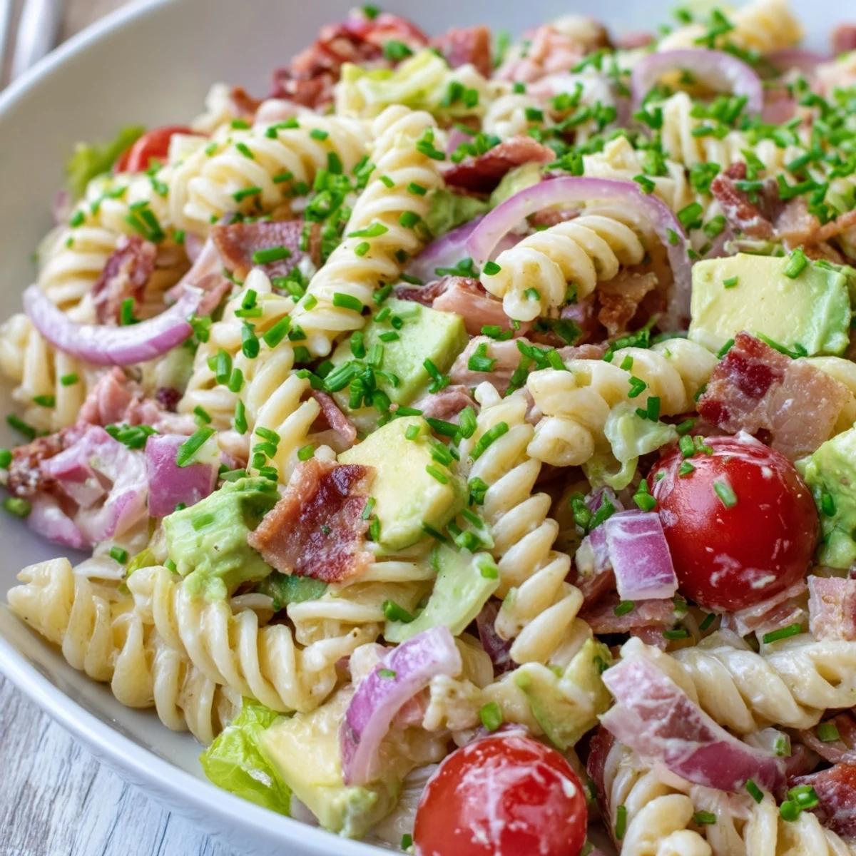 BLT Pasta Salad, a colorful mix of pasta, bacon, and tomatoes, awaits on a plate.