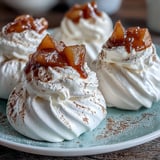 A trio of Mini Hot Toddy Pavlovas, each topped with bourbon-soaked pears and a dusting of cinnamon.