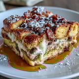 A plated slice of Monte Cristo Breakfast Casserole drizzled with maple syrup and berries.