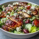 Colorful Greek salad bowl with tender grilled chicken, crisp cucumbers, ripe tomatoes, and tangy Kalamata olives.  