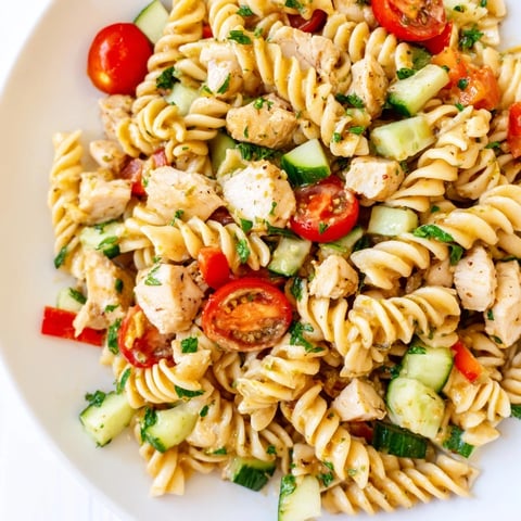Tender honey mustard chicken pasta salad with crisp veggies and fresh parsley garnish.