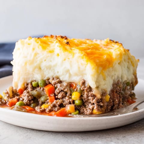 Close-up of savory Rustic Shepherds Pie, warm steam rising, topped with browned, melted cheese.