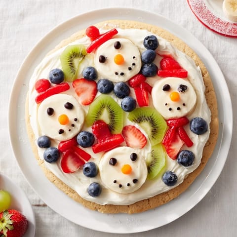 Freshly-made Melting Snowman Fruit Pizza: a festive dessert with creamy frosting and bright berries.