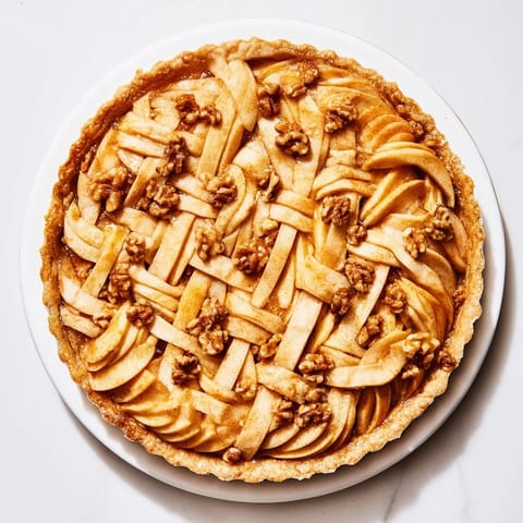A warm slice of The Lattice Orchard displays glistening apples atop a sweet, nutty filling.