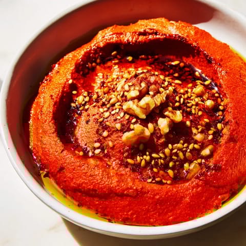 A beautifully textured bowl of Muhammara, with swirls of red pepper and glistening olive oil.