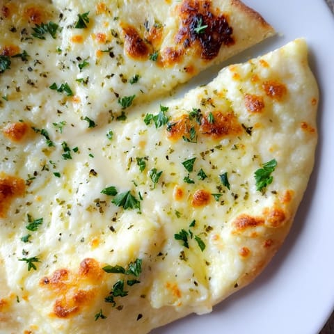 Sliced Creamy Garlic White Pizza reveals a velvety garlic cream sauce base and fresh parsley garnish.  