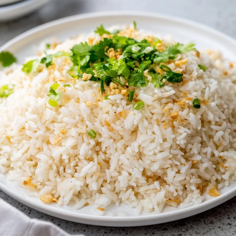Spoonful of tender jasmine rice garlic glistening with golden garlic oil, ready to complement savory vegetables or a spicy curry.