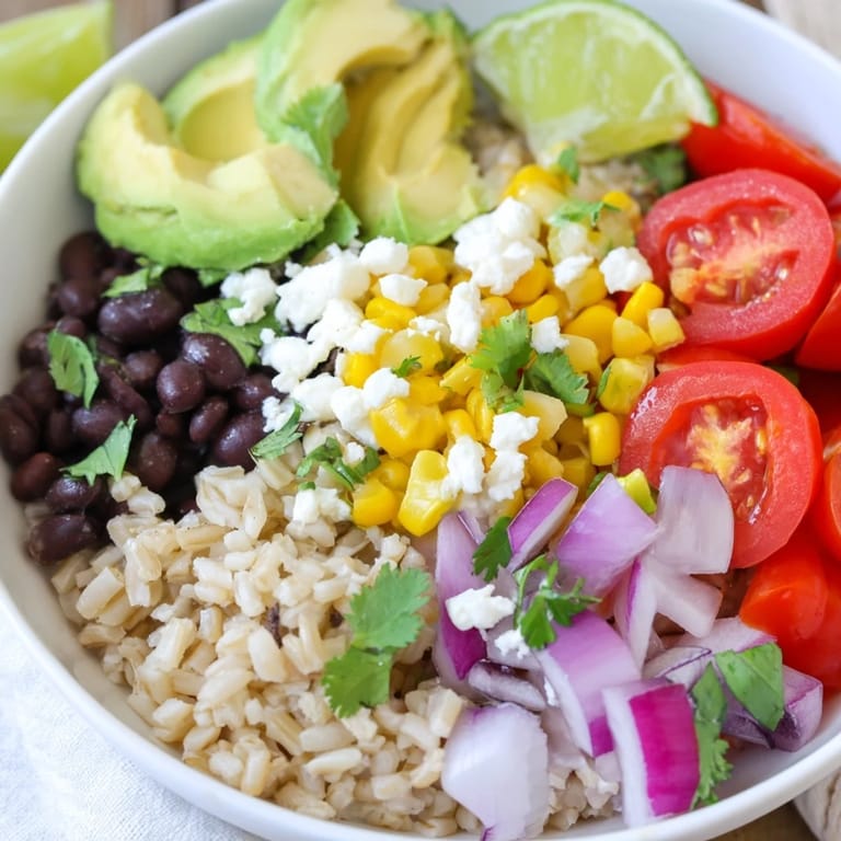 The hearty Brown Rice Burrito Bowl features fluffy rice, seasoned beans, sweet corn, and tangy sour cream with a lime wedge for brightness.