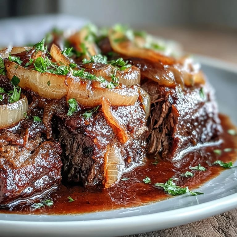 Tender slices of Savory Crock Pot French Onion Pot Roast topped with gooey melted Gruyère and fresh parsley garnish.