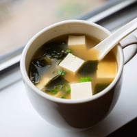 Silky cubes of tofu and tender wakame seaweed swim in a warm, savory miso broth, garnished with fresh scallions.