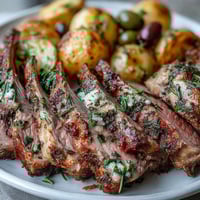 Golden-brown rack of lamb with herb rub and green olive potatoes, a perfect romantic dinner for two.